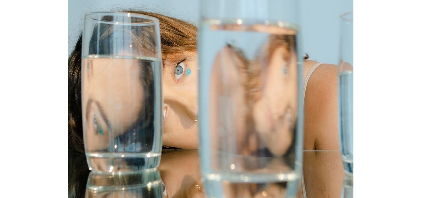Artistic view of woman's hair and eye through filled glasses